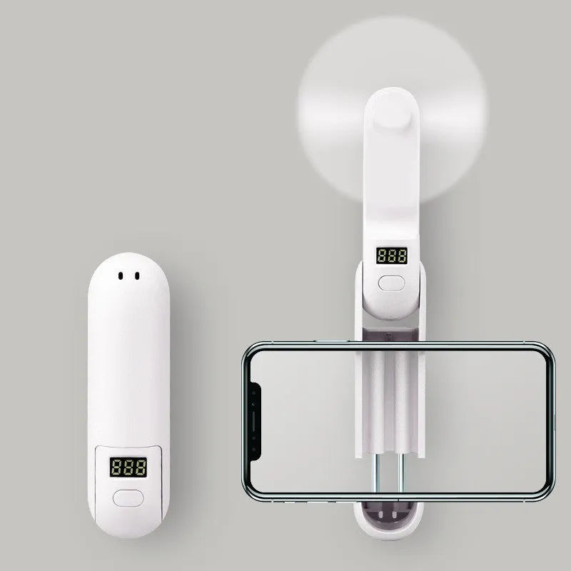 Green folding mini fan with plastic blades collapsed for storage beside USB charging cable