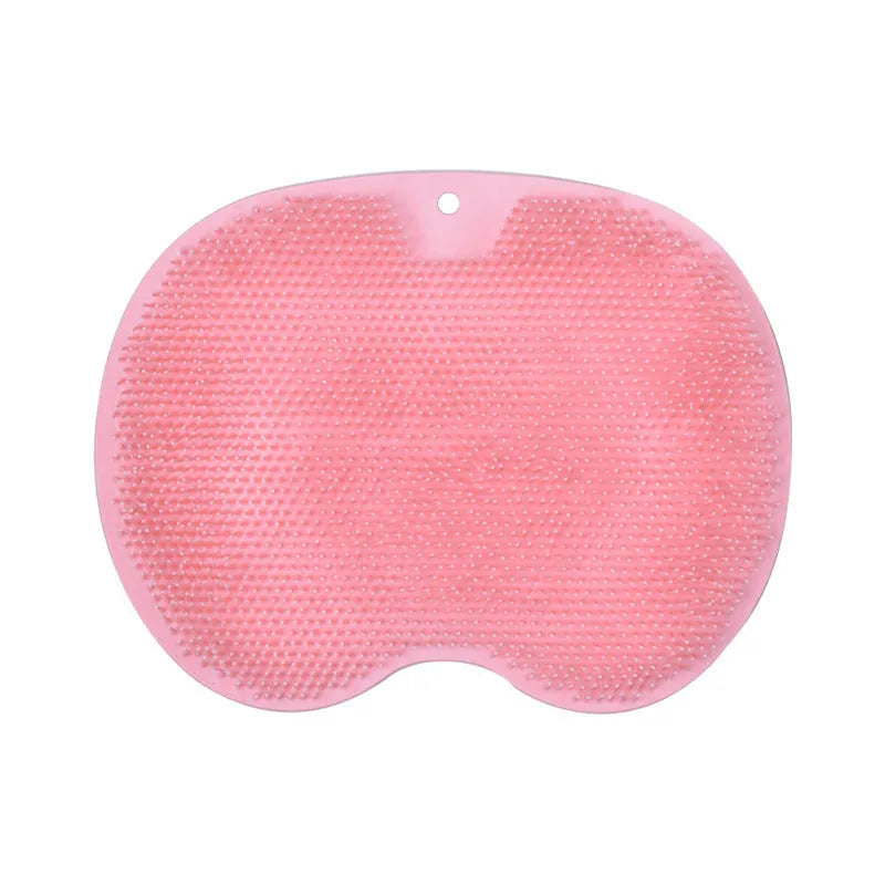 Orange non-slip massage bath brush with suction cups and soft silicone bristles on a bathroom floor.