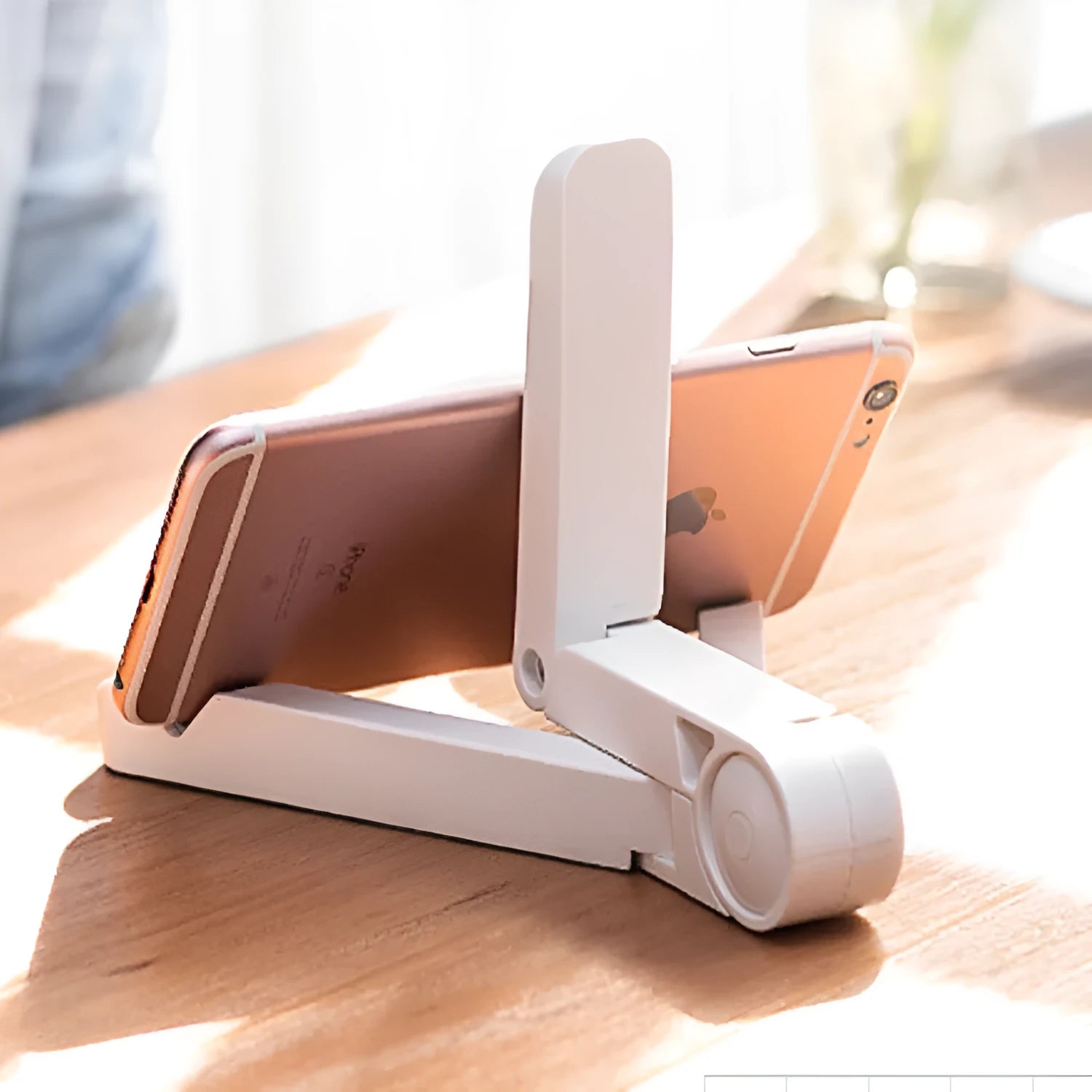 Black foldable tablet stand holding a smartphone in landscape mode on a desk, showing its compact folded size.
