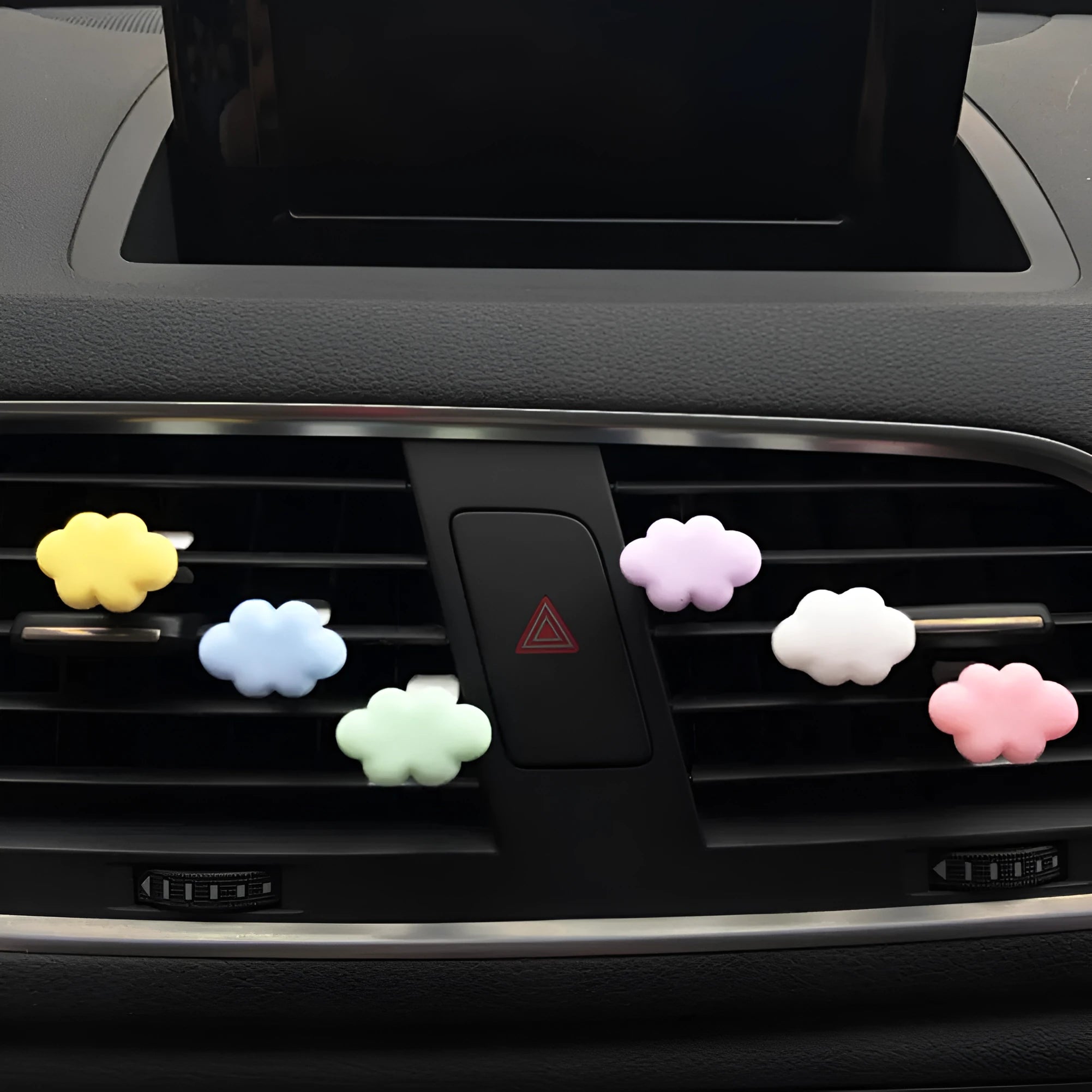 Small colourful resin car fragrance clip shown in multiple colours on a car air vent.