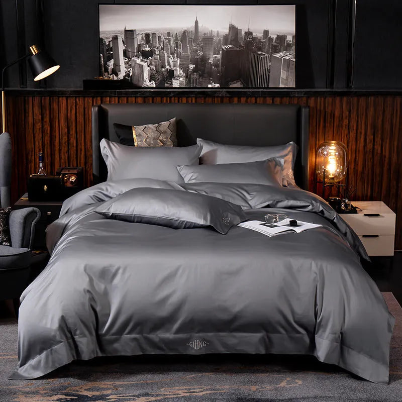 Four-piece cotton satin quilted bedding set with duvet cover, sheet, and pillowcases in a bedroom setting