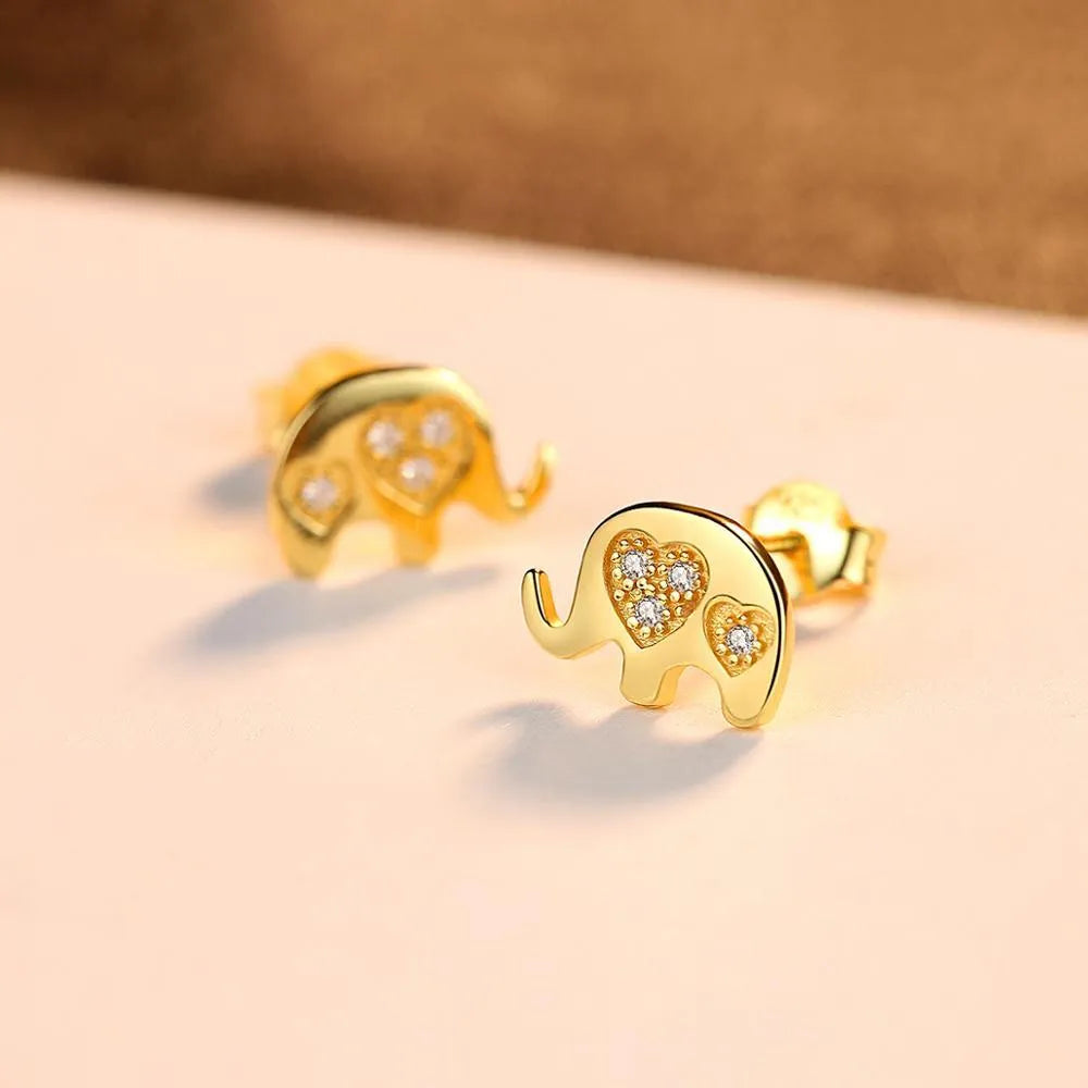 Small geometric silver stud earrings with gold or silvery finish on a grey background.