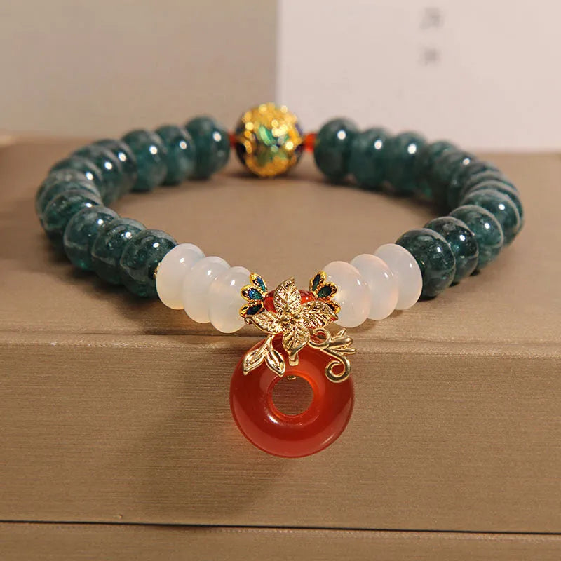 Close-up of a women's crystal bracelet with blue jade beads, red agate, and a silver peace buckle closure.