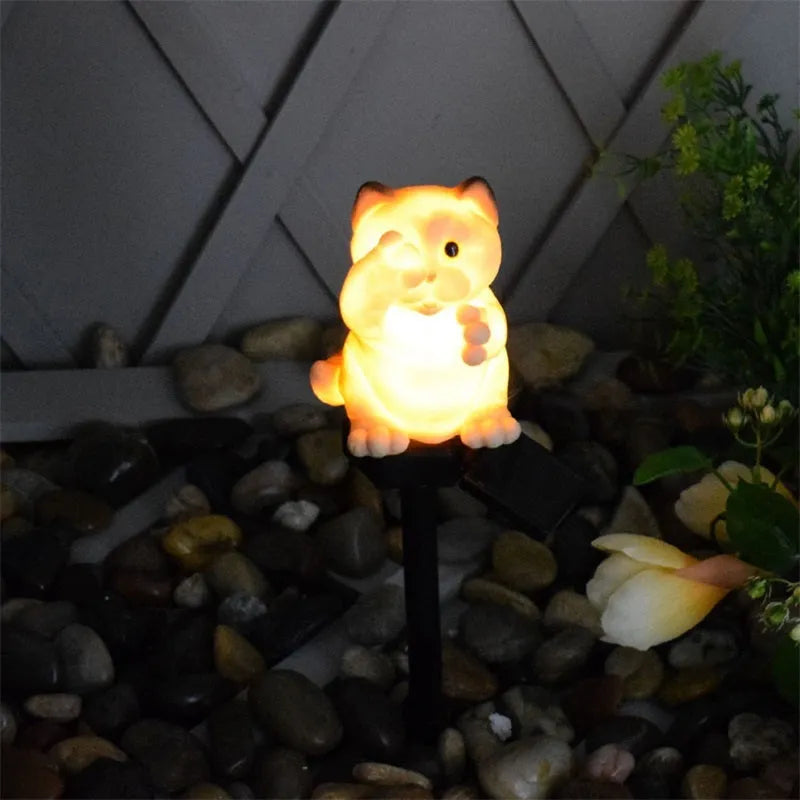 Brown resin solar-powered cat lawn light with LED illumination in a garden setting.