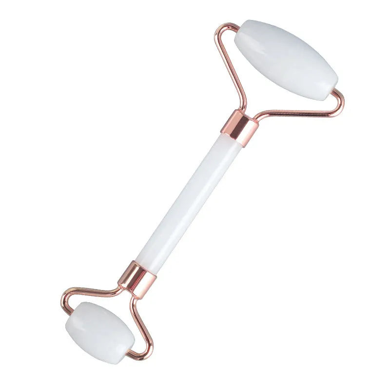 White jade double-headed facial roller and gua sha board set on a flat surface.