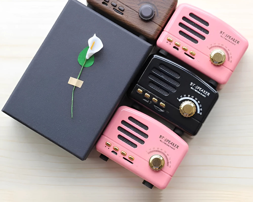 Vintage wood effect Bluetooth speaker in pink, black, and wood grain colour options showing compact 93x70x59mm size