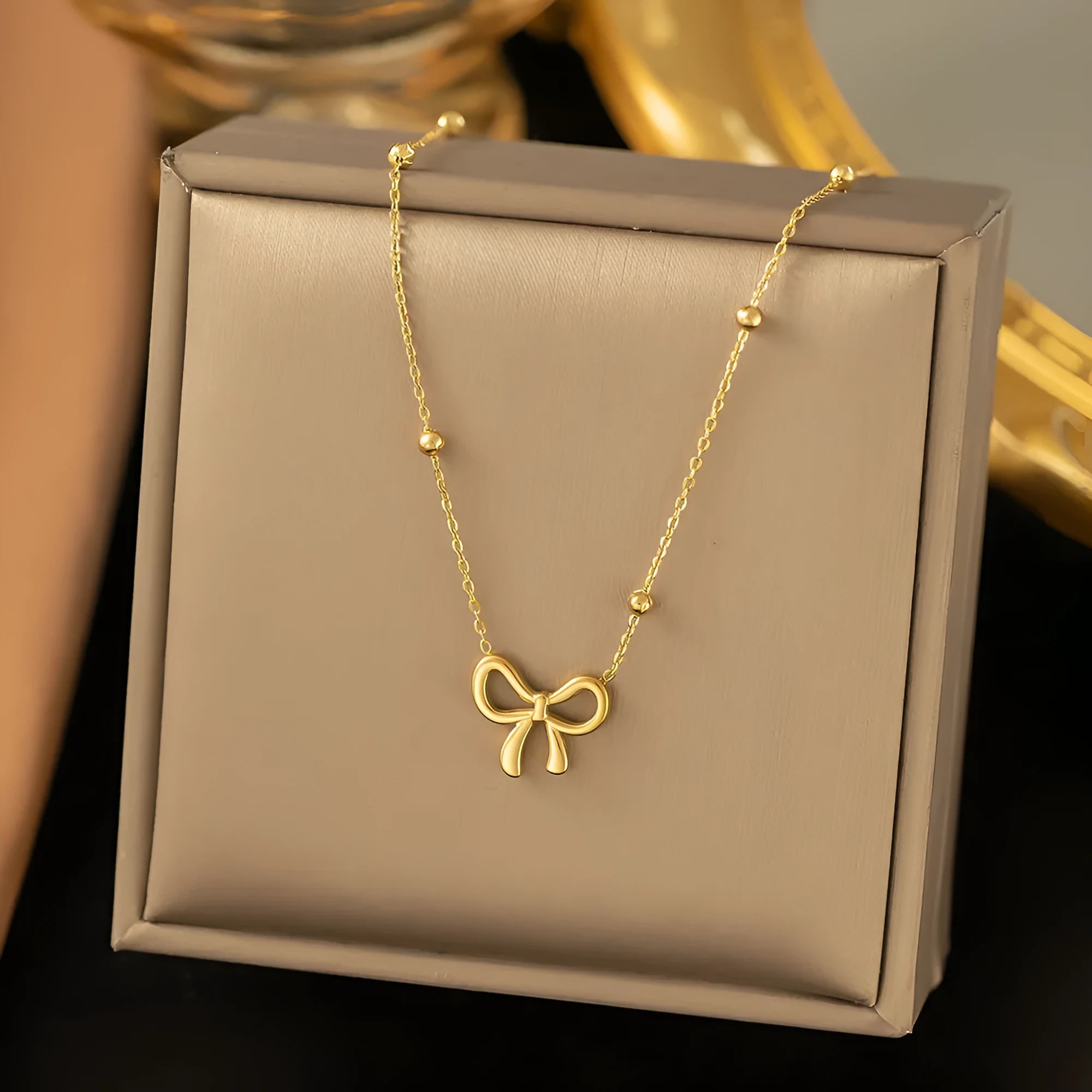 Gold-coloured bow pendant necklace on a cross-link chain, adjustable from 41 to 50 cm.