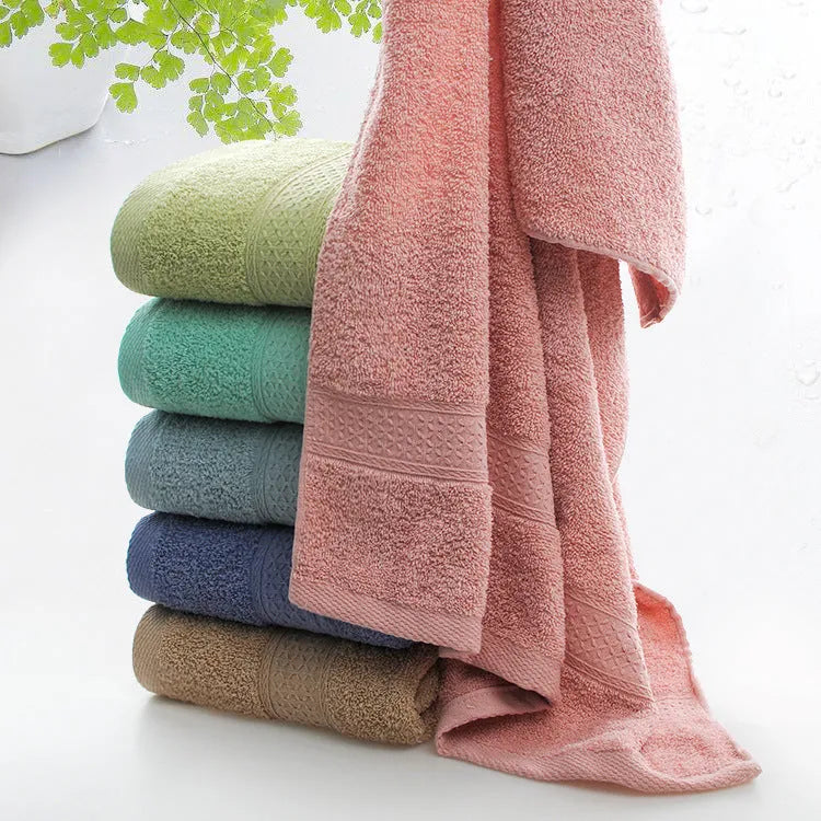 A pile of thickened cotton bath towels in various colours including apple green, dark blue, and light pink.