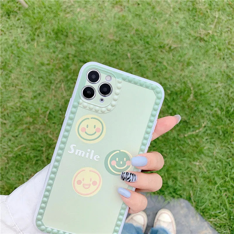 Green iPhone case with geometric pattern and smiley face polka dot design on a soft TPU back cover.