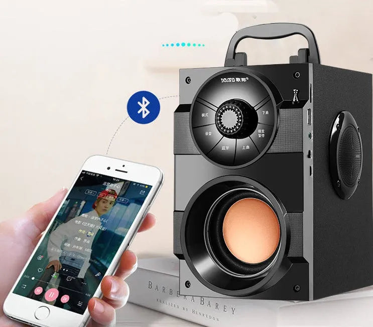 Black portable mini home audio system with subwoofer, satellite speakers, and USB charging cable on a desk.