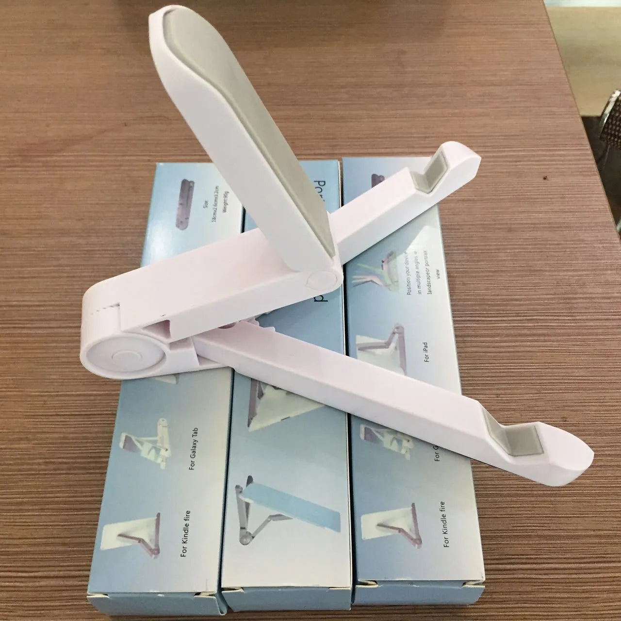 Black foldable tablet holder open in landscape mode holding a smartphone, showing its compact size and non-slip rubber surface.