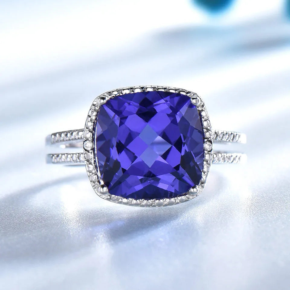 Women's sterling silver ring with a blue tanzanite gemstone on a finger.