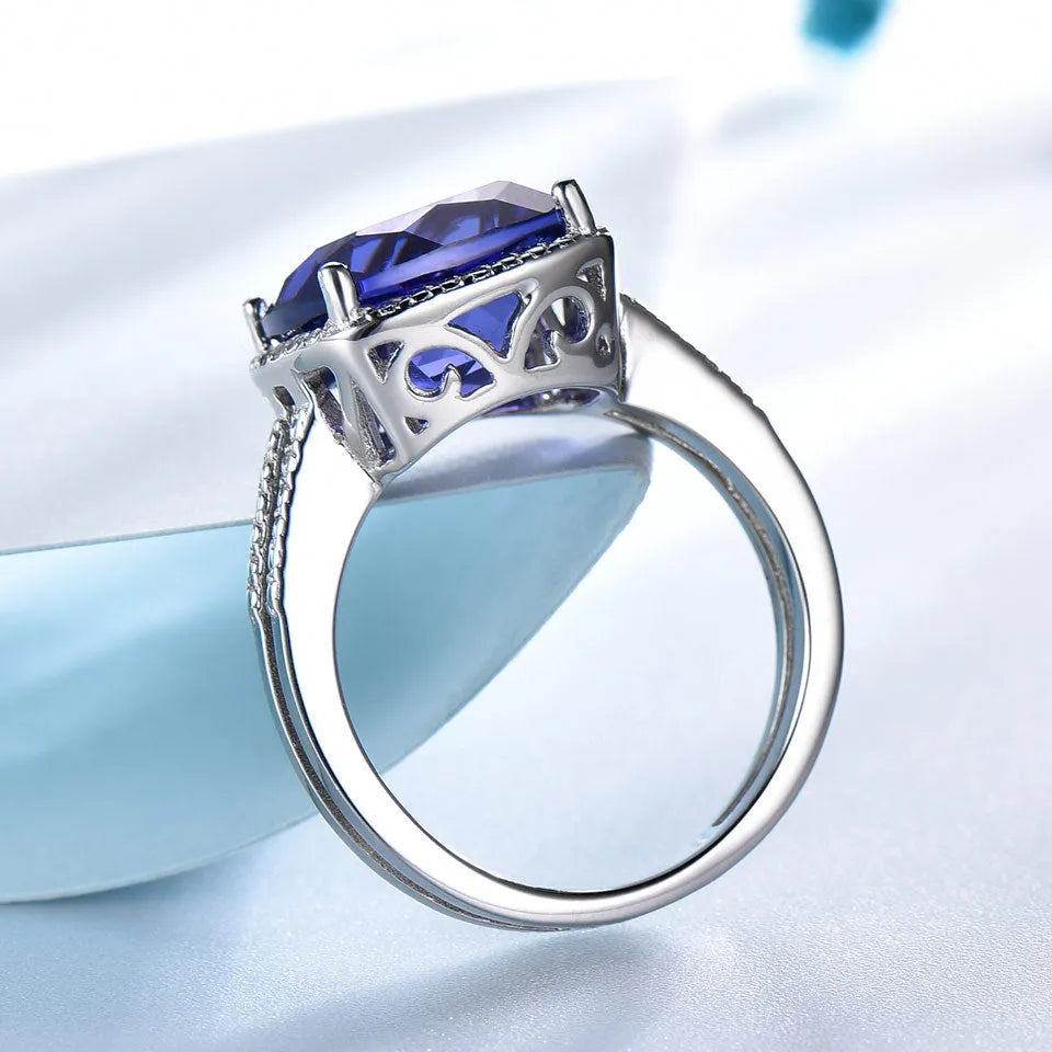 Women's sterling silver ring with a blue tanzanite gemstone on a finger.