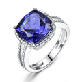 Women's sterling silver ring with a blue tanzanite gemstone on a finger.