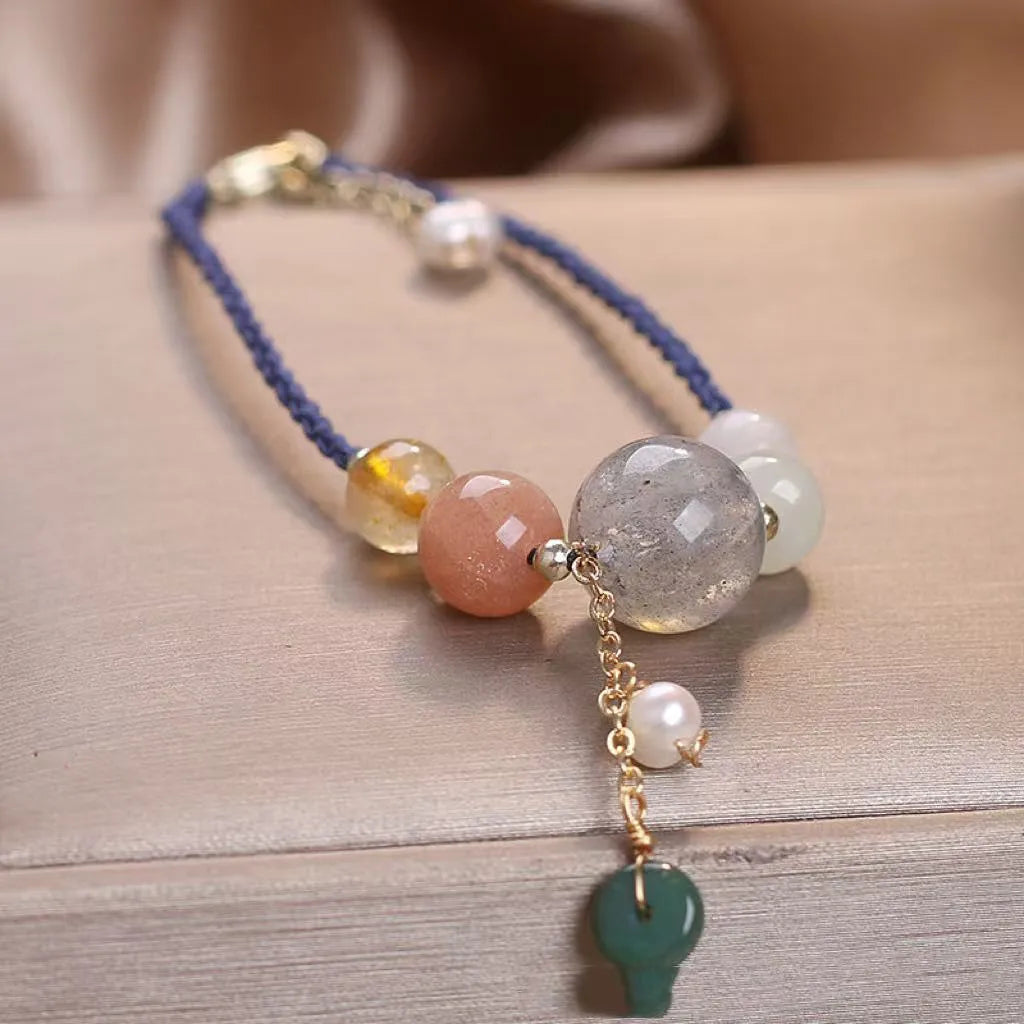 Women's hand-woven bracelet with a silver peace buckle charm and crystal sequin details on a blue band.