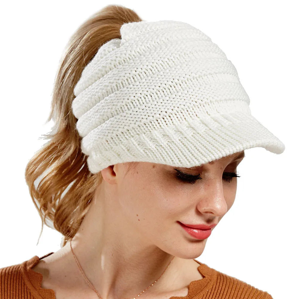Woman wearing a thick knitted beanie with her ponytail pulled through the hole in the crown.