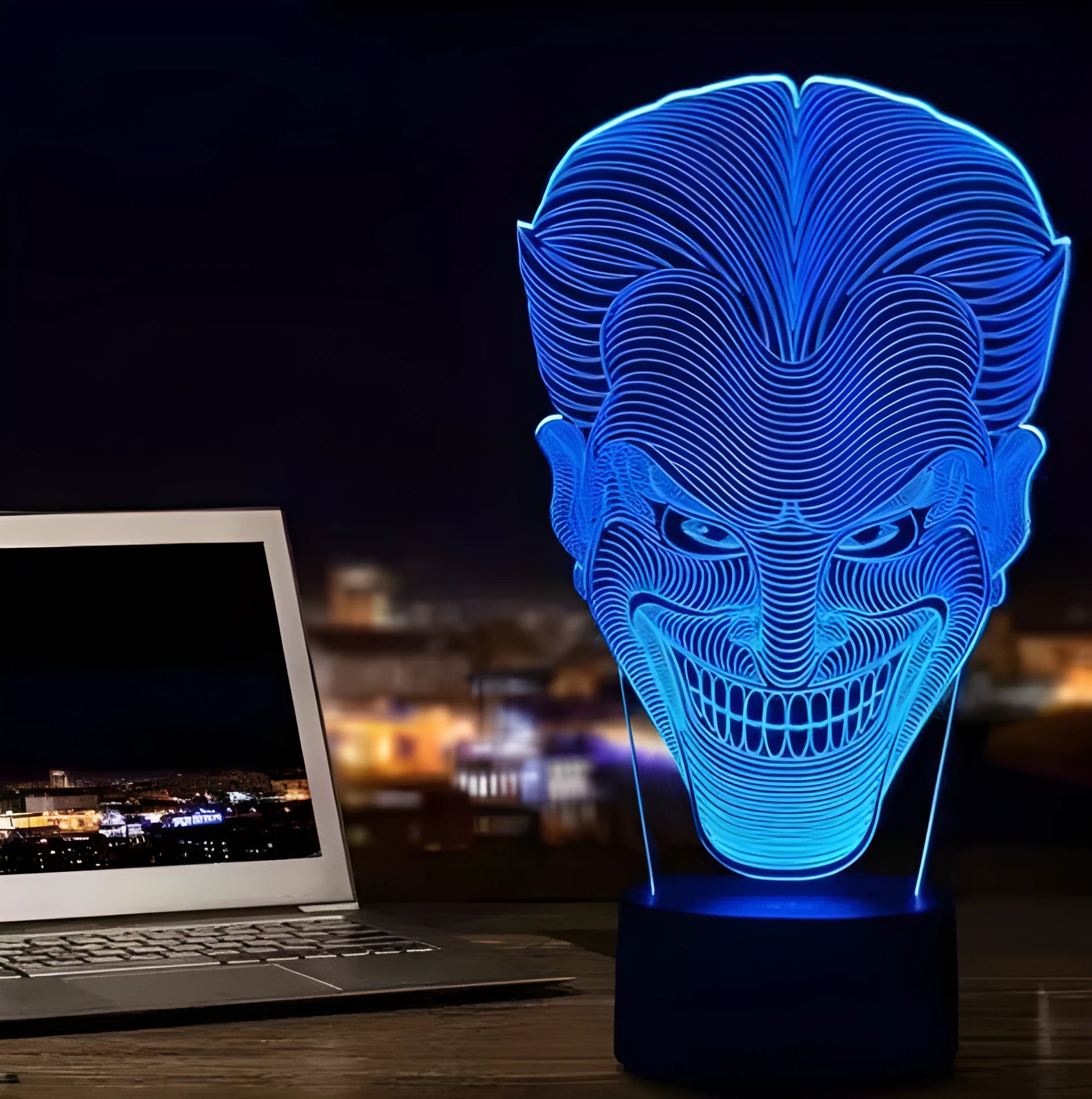 A 3D LED table lamp showing multiple colour lights, sitting on a square base with a USB cable and remote control.