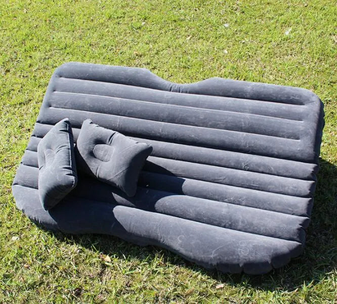 Black inflatable car bed with flocked surface and pillows set up in a car's back seats