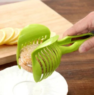 A black or green plastic tomato slicing holder on a kitchen worktop.