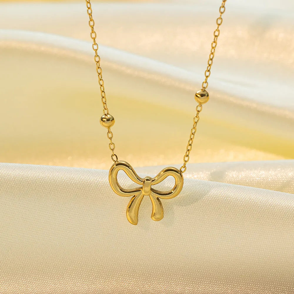 Gold-coloured bow pendant necklace on a cross-link chain, adjustable from 41 to 50 cm.