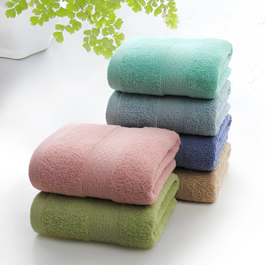 A pile of thickened cotton bath towels in various colours including apple green, dark blue, and light pink.