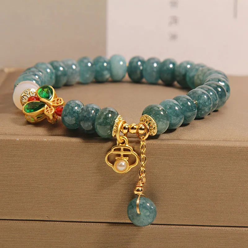Blue water jade abacus beads bracelet with white agate, butterfly motifs and rhinestone accents on alloy band
