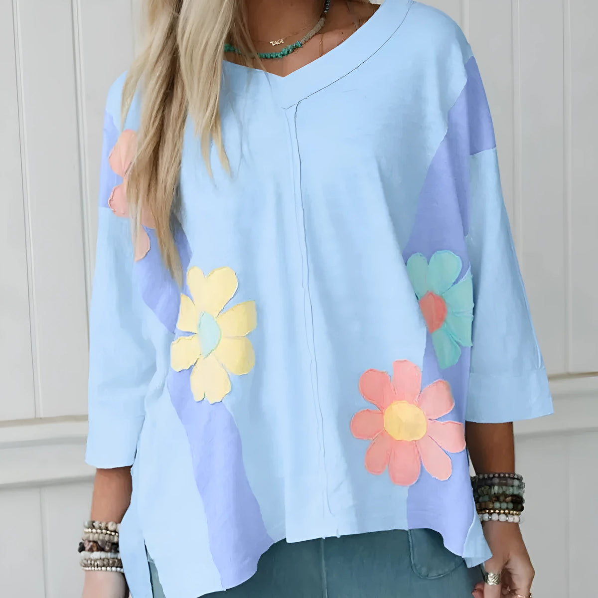 Light blue T shirt with flower patch, exposed seam bracelet sleeves, and oversized fit in sizes S M L XL
