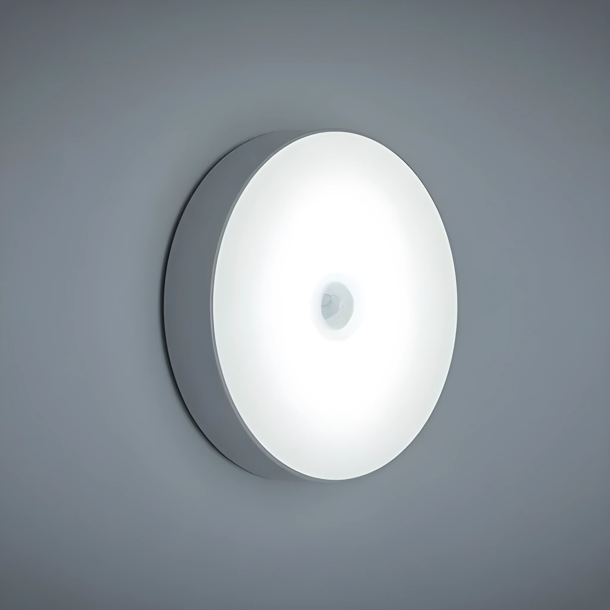 Small circular white motion sensing LED night light with USB charging cable and adhesive tape.