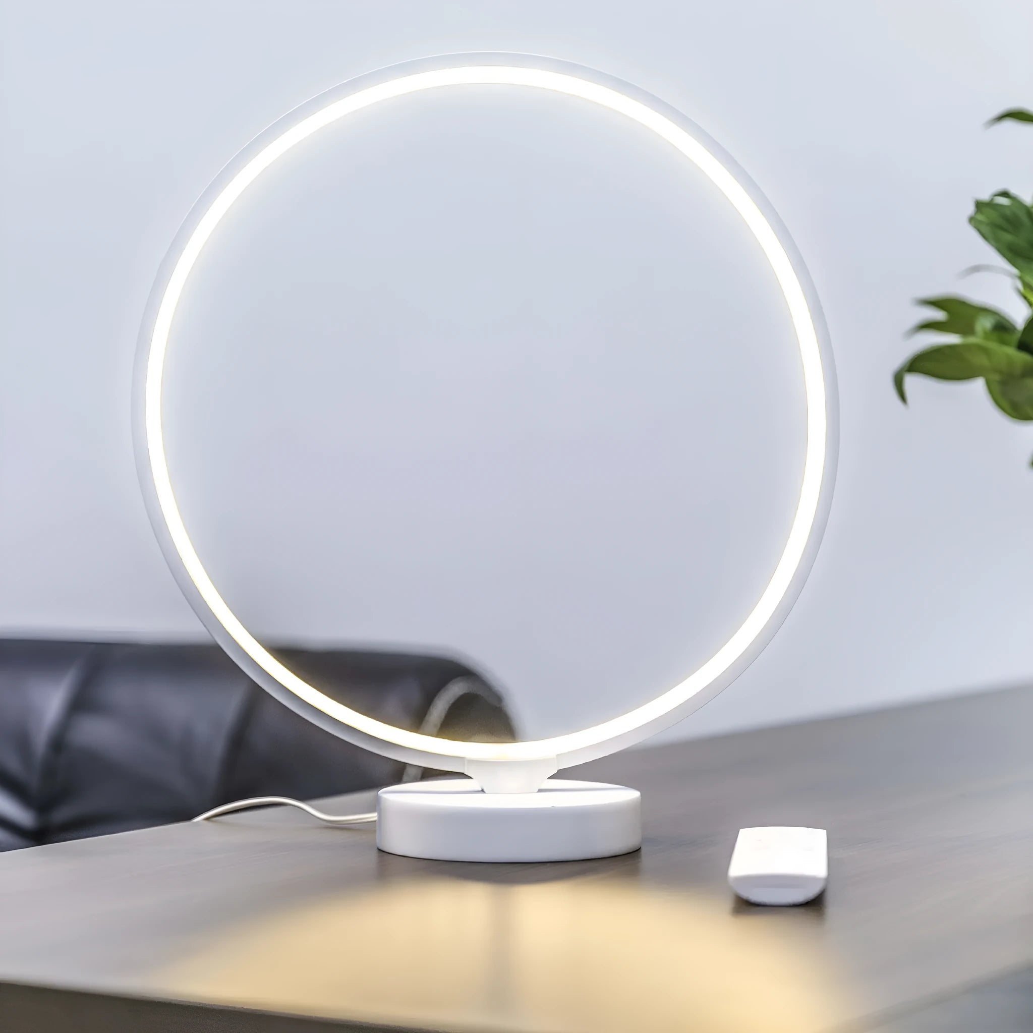 White Full Moon shaped mood lamp with remote control on a wooden desk.
