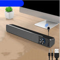Black and white compact 2.0 channel desktop speakers with USB cable on a wooden desk.
