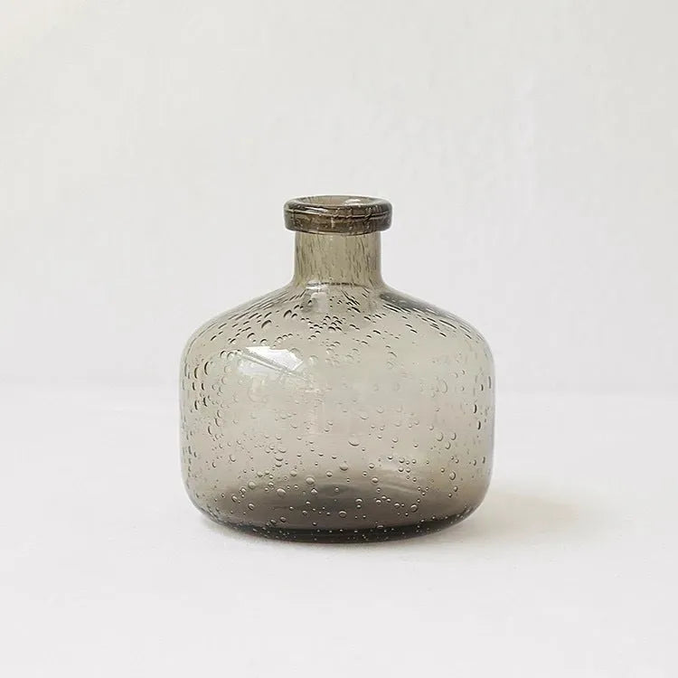 Grey geometric bubble-shaped stained glass vase on a wooden surface.
