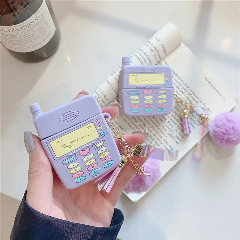 Purple silicone clamshell case for Apple AirPods with a small fur ball pendant attached.