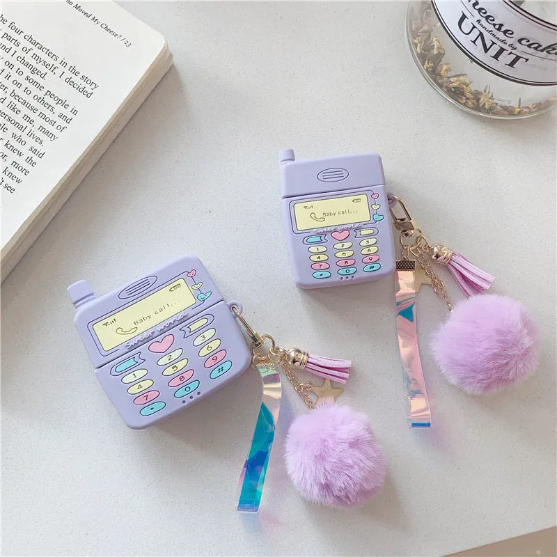 Purple silicone clamshell case for Apple AirPods with a small fur ball pendant attached.