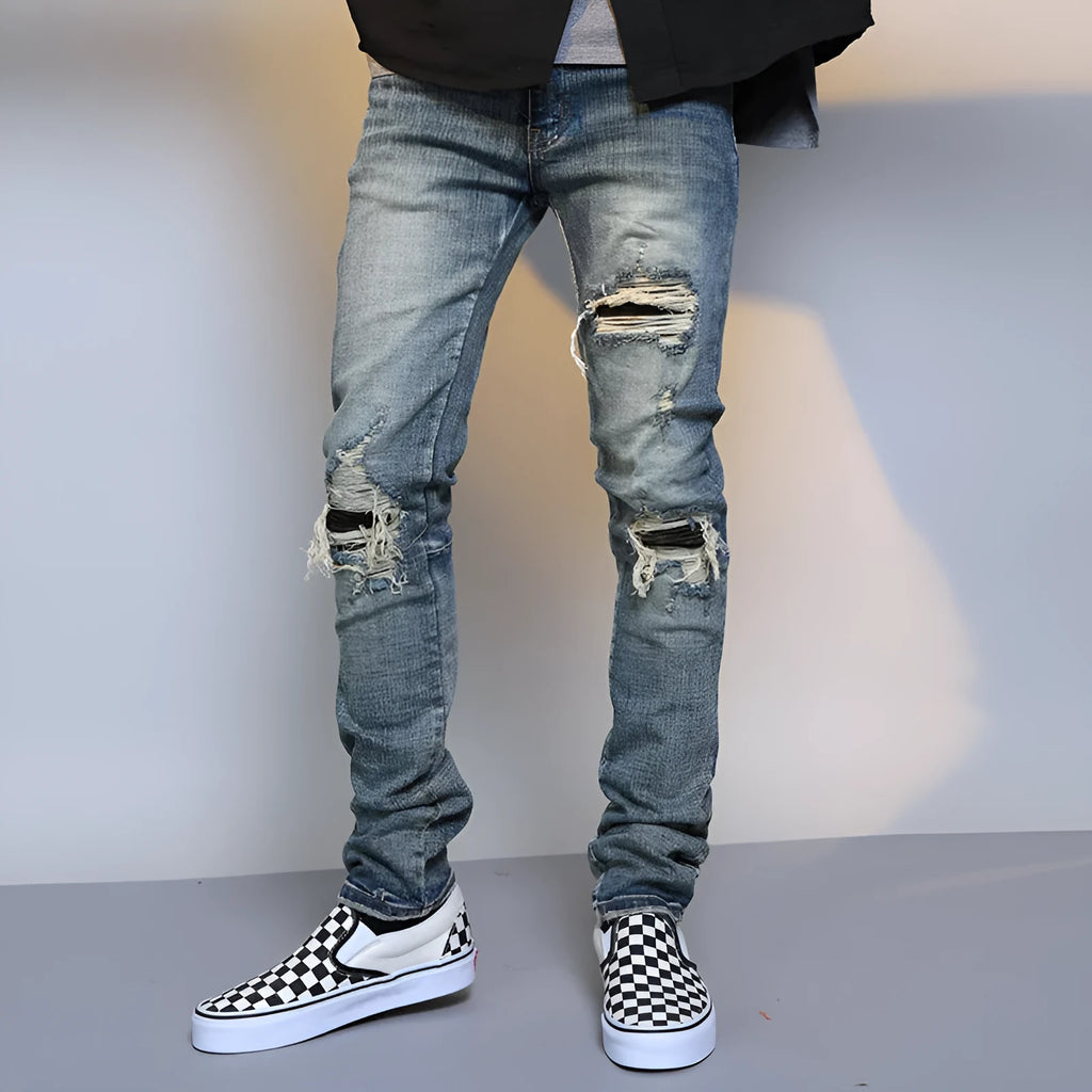Mens ripped washed blue cotton denim jeans with middle-waisted zip fly, side view on model