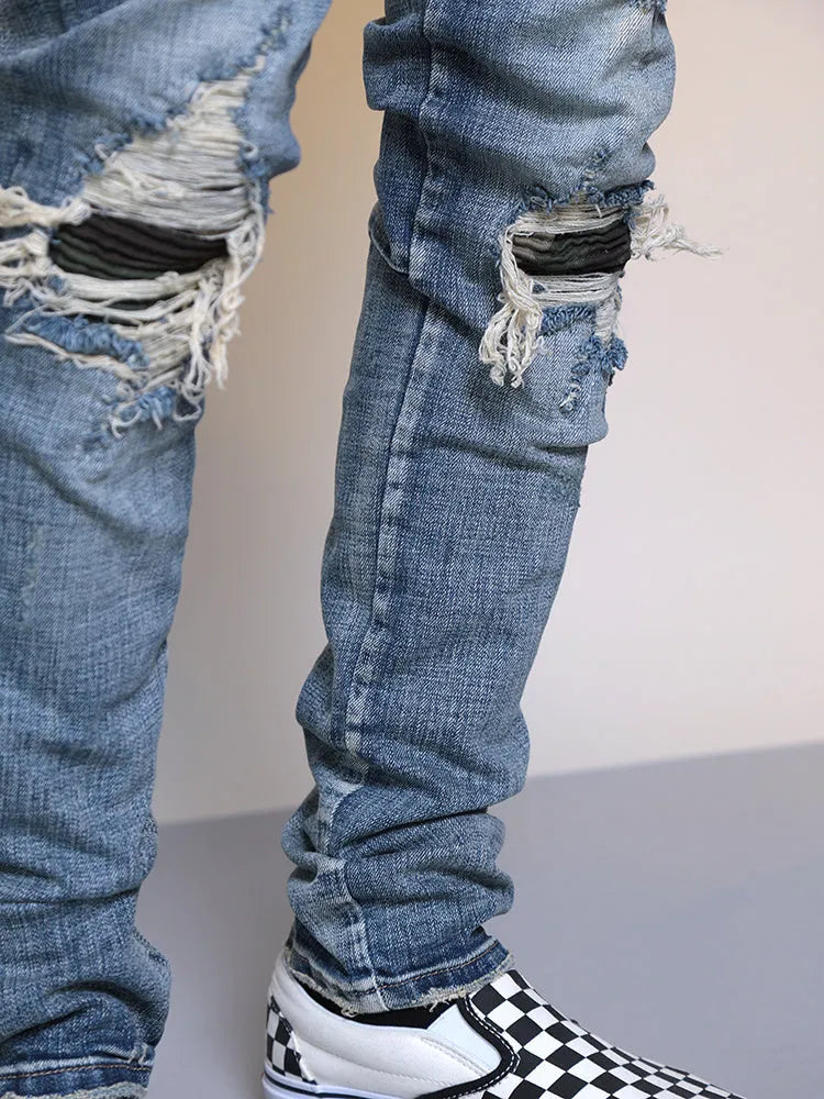 Mens ripped washed blue cotton denim jeans with middle-waisted zip fly, side view on model