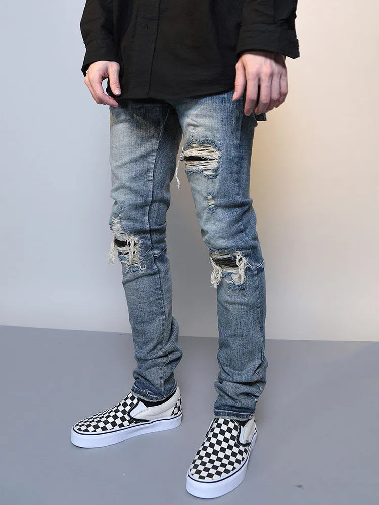 Mens ripped washed blue cotton denim jeans with middle-waisted zip fly, side view on model