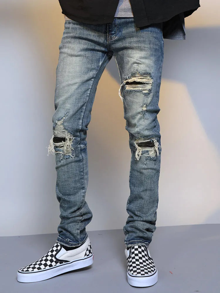 Mens ripped washed blue cotton denim jeans with middle-waisted zip fly, side view on model