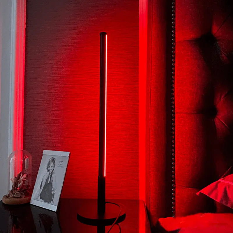 Nordic minimalist black or gold LED table lamp with RGB colour touch remote control on a bedside table.