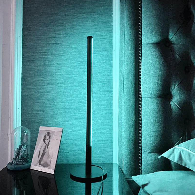 Nordic minimalist black or gold LED table lamp with RGB colour touch remote control on a bedside table.