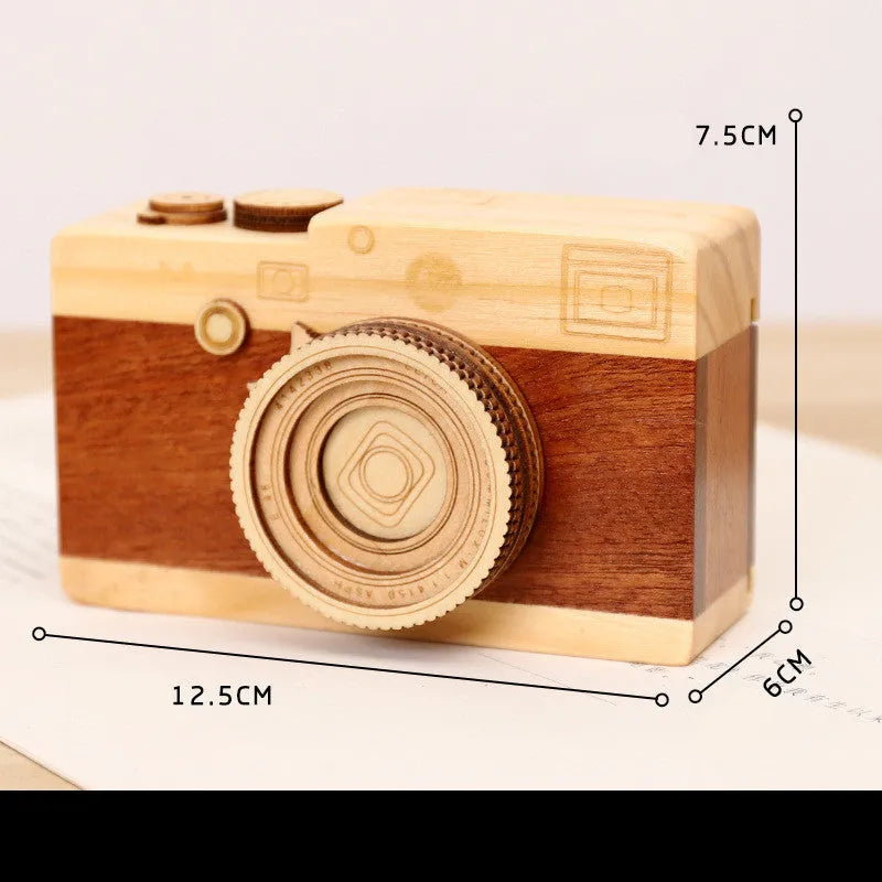 Cute camera-shaped wooden music box with rotating mechanism on pine wood base.