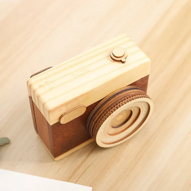 Cute camera-shaped wooden music box with rotating mechanism on pine wood base.