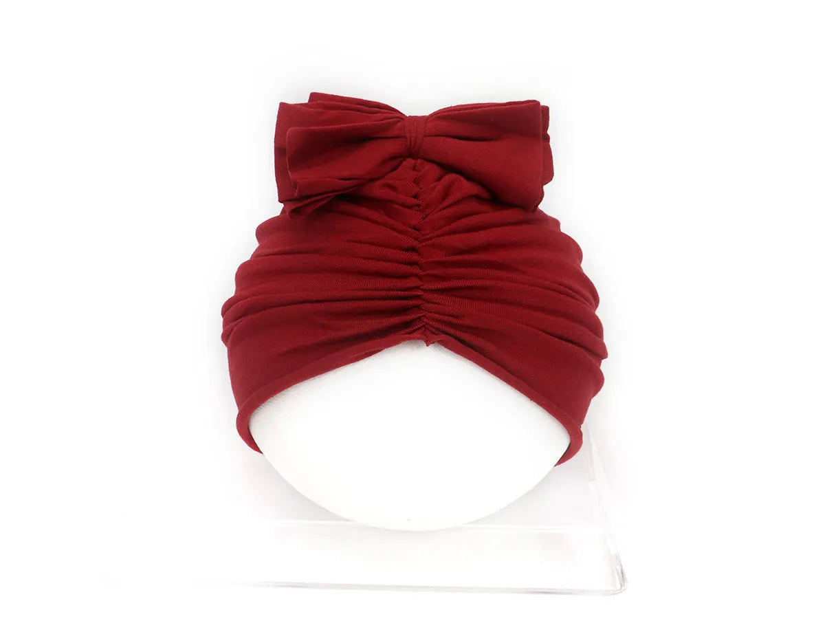 Soft acrylic knitted bonnet for a baby girl, shown in a solid colour, suitable for 0-28 month olds.