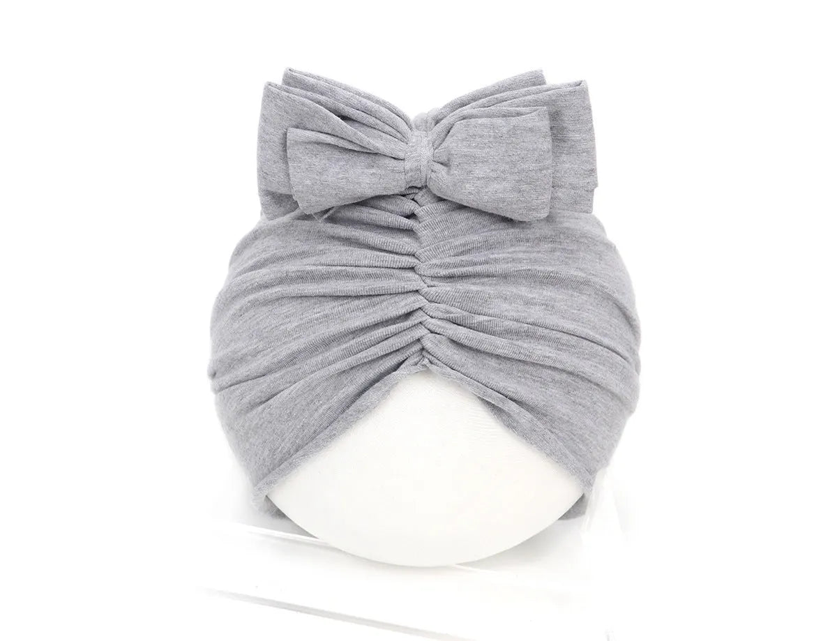 Soft acrylic knitted bonnet for a baby girl, shown in a solid colour, suitable for 0-28 month olds.