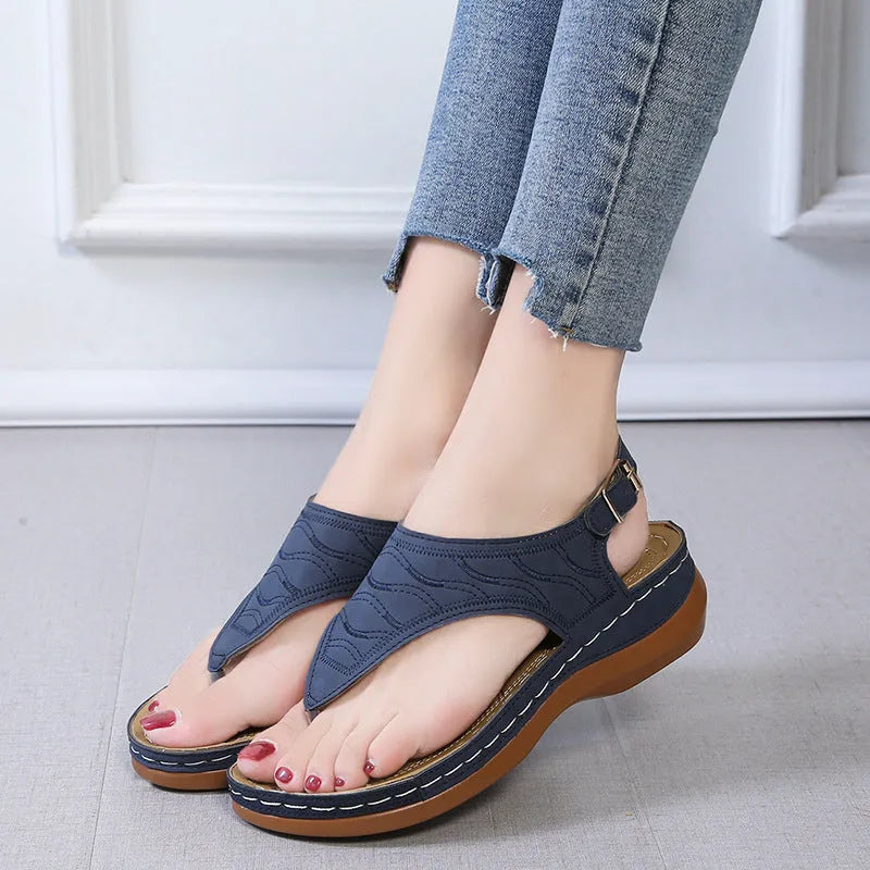 Women's red wedge heel flip flop sandals with an adjustable buckle strap on a white background.