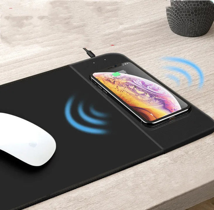 Black wireless charging mouse pad with cartoon design, showing RGB lighting and USB cable.