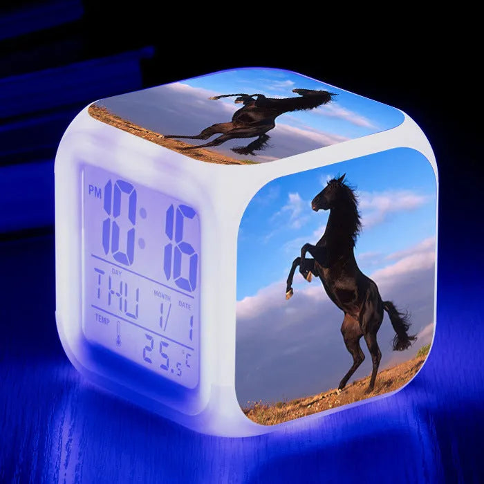 Small square cartoon-style LED alarm clock showing digital time and temperature on a colourful display.