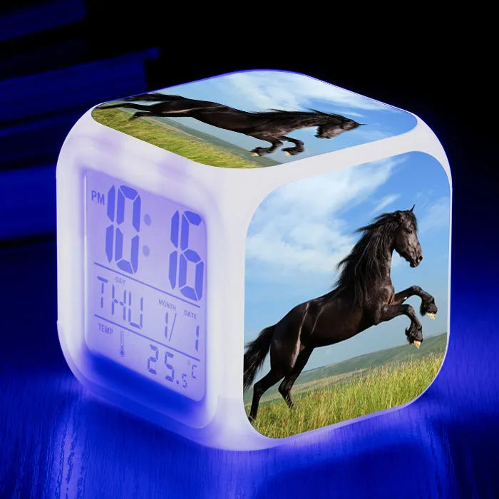 Small square cartoon-style LED alarm clock showing digital time and temperature on a colourful display.