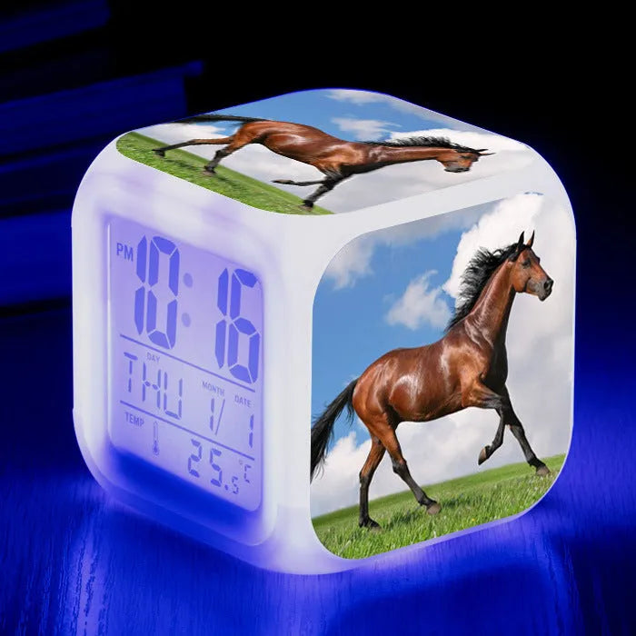 Small square cartoon-style LED alarm clock showing digital time and temperature on a colourful display.