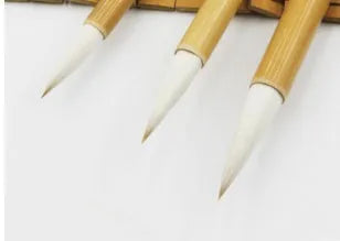 Set of three Chinese calligraphy brushes with wool hair tips and bamboo handles in large, medium, and small sizes.
