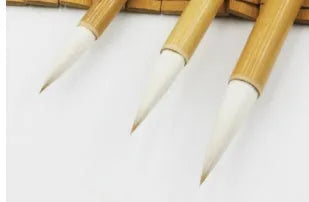 Set of three Chinese calligraphy brushes with wool hair tips and bamboo handles in large, medium, and small sizes.